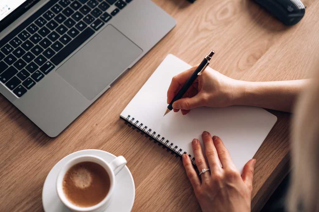 Woman Sitting at a Wooden Table and Writing in a Diary Free Stock Photo